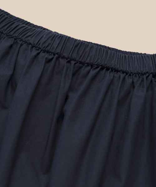 Close-up of the elastic waistband on the Lauren Skirt in black, showcasing its lightweight comfort and cotton-like feel, set against a beige background.