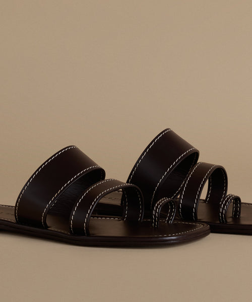 Pair of black leather sandals on a beige background