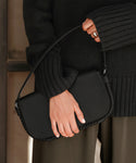 Someone, visible from hands to torso and dressed in a dark knit sweater with olive green pants, holds the Brooke Shoulder Bag, distinguished by its Vachetta leather and short strap.