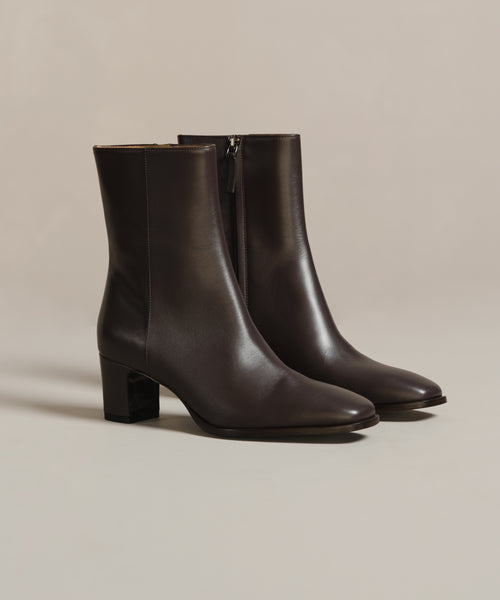 The Leather Bobby Boot is a sleek, dark brown ankle boot for women, featuring a side zipper and block heels. Displayed on a neutral background, it’s an effortlessly versatile choice for any occasion.