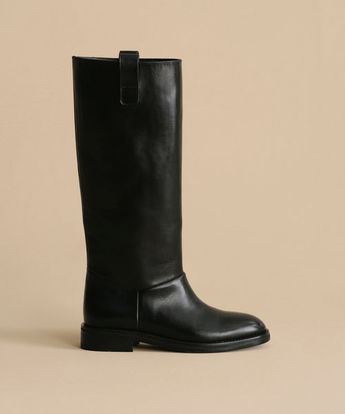 The Leather Stowe Boot is a structured black calf leather knee-high boot with a low heel and top pull tab, shown against a plain beige background.