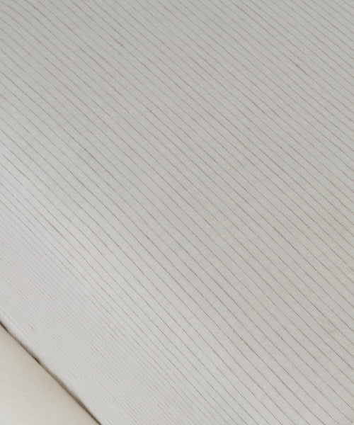 Close-up of the Dusk Linen Fitted Sheet, crafted in Portugal, with thin, evenly spaced flax stripes running diagonally across light fabric for a subtle, minimalist texture.