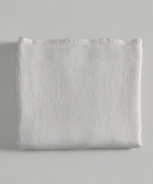 The Dusk Linen Flat Sheet, featuring a subtle ribbed texture in crisp white, is neatly folded on a light gray surface—an ideal choice for luxury bedding.