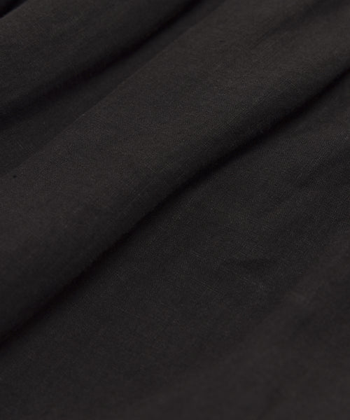 Close-up of the Linen Logan Pant in black, featuring soft, flowing folds and a smooth, slightly textured surface. Lightweight and gently draped, these pants are ideal for everyday wear.