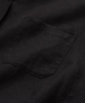 A close-up of the Linen Logan Shirt in black highlights its classic style, with a small chest pocket and simple stitching that emphasize its relaxed design.