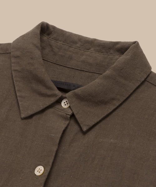 A close-up of the Linen Logan Shirt highlights its boxy fit, pointed collar, and light buttons, showcasing effortless style against a beige background.