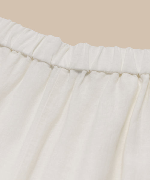 Close-up of the Linen Logan Pants ivory waistband, highlighting gathered linen fabric against a beige background—ideal for effortless everyday style.