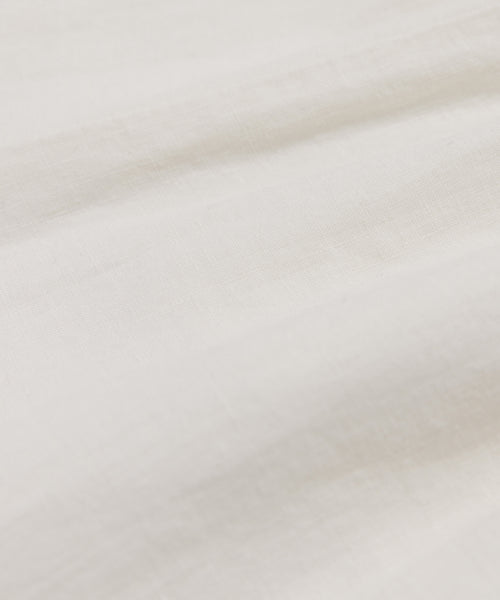 Close-up of the Linen Logan Pant’s white, textured fabric with gentle folds and subtle lines. The smooth, lightweight material is slightly wrinkled, evoking a relaxed feel—perfect for everyday wear.