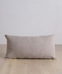 The Linen Lumbar Pillow with a feather down insert is placed on a wood floor.