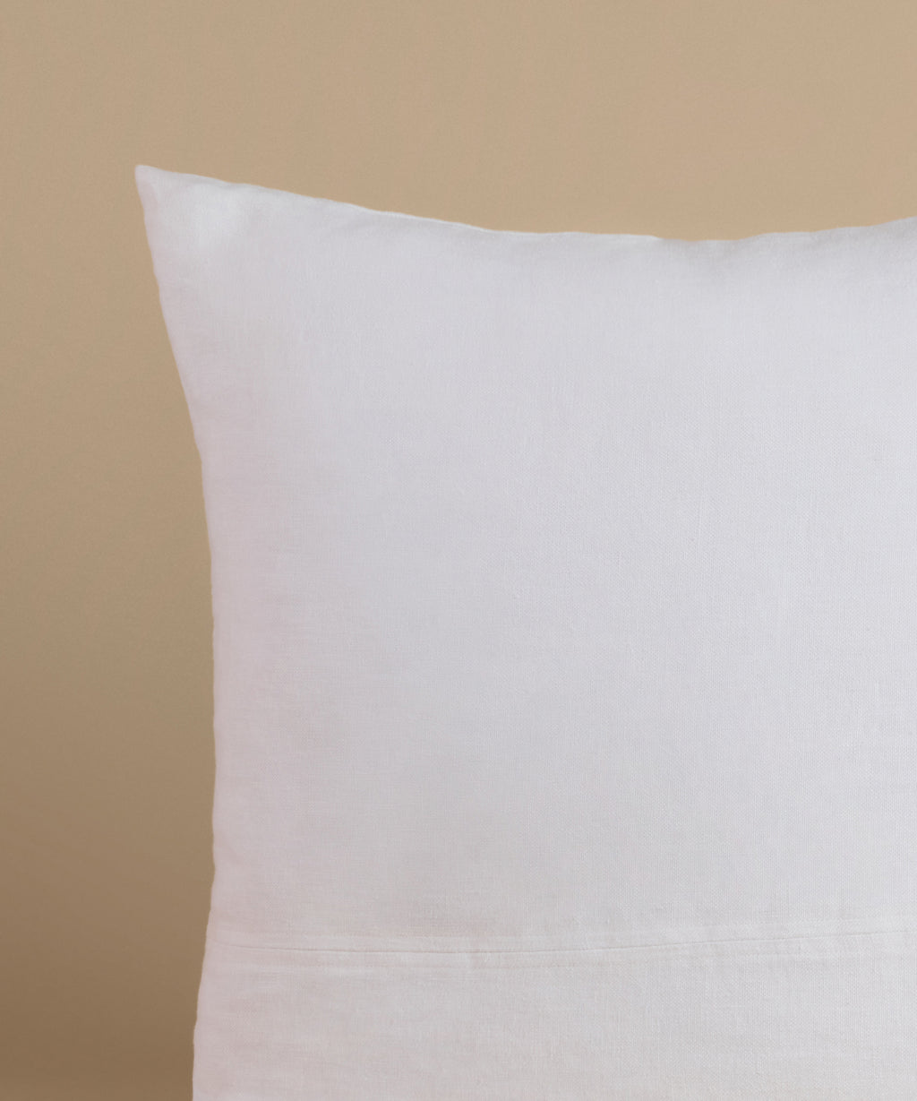 A white linen pillow against a beige background.