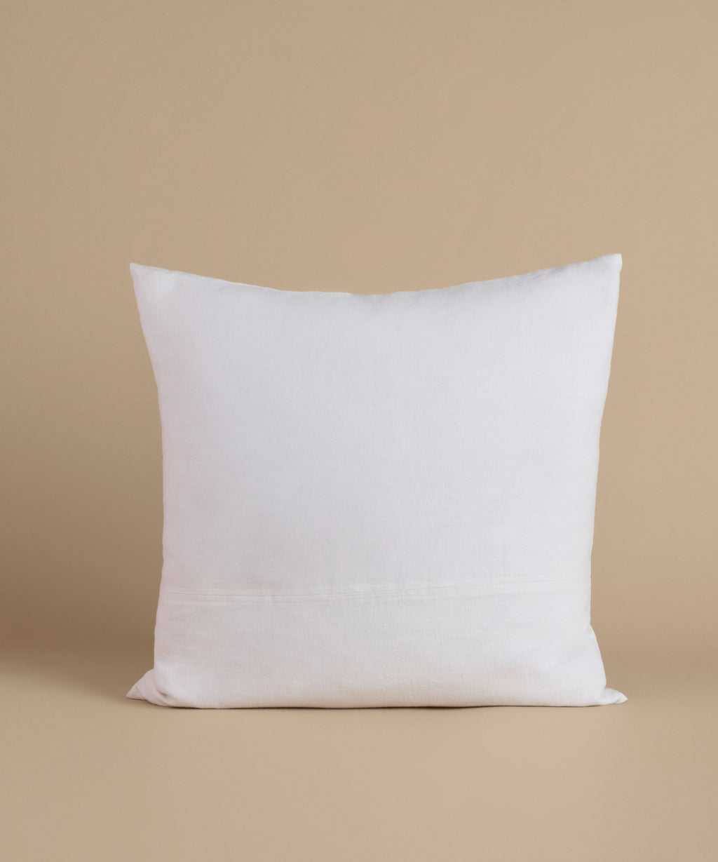 A white linen pillow against a beige background.