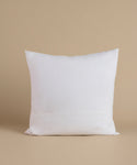 A white linen pillow against a beige background.