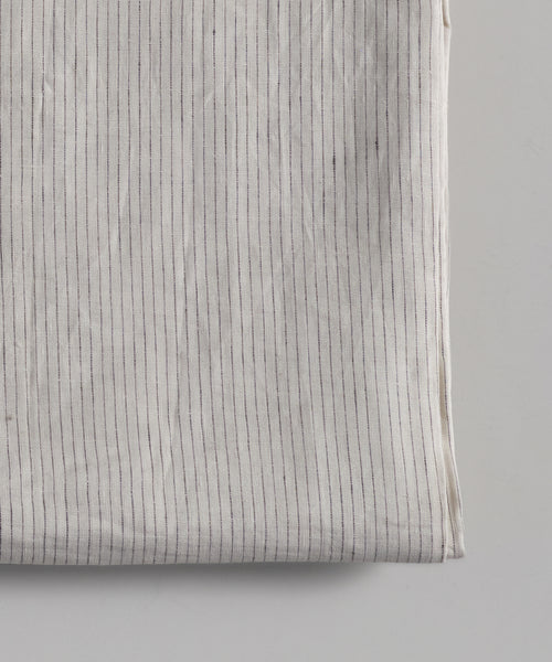 A close-up of the Linen Tablecloth, made in Portugal, shows thin, vertical, evenly spaced black stripes on a plain background.