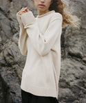 Person wearing an ivory Loma Pullover against a rocky background