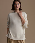 Woman wearing an ivory Loma Pullover against a brown background