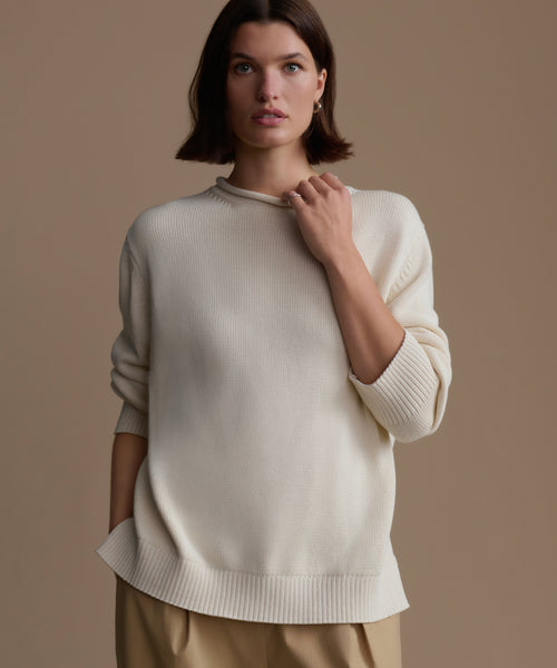Woman wearing an ivory Loma Pullover against a brown background