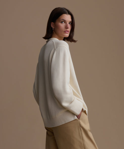 Woman wearing an ivory Loma Pullover and beige pants against a brown background