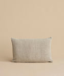 The Luna Lumbar Pillow, featuring a textured beige fabric cover and feather down insert, is placed against a matching beige background.