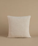A textured cream color pillow against a beige background.