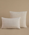 A textured cream color pillow against a beige background.
