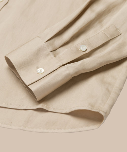A close-up of the Madeline Shirt’s cuff and sleeve showcases its white buttons and fine stitching on beige linen fabric—the perfect detail for a spring-ready style.