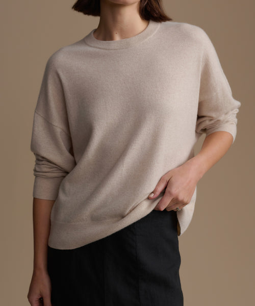 Woman wearing a beige cashmere sweater against a brown background