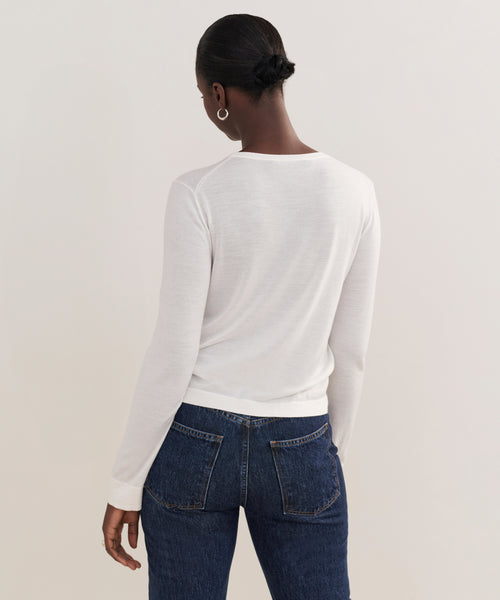 Seen from behind, a person with short dark hair in a low bun wears the Mercer Crewneck and blue jeans, standing against a plain light background.