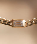 Close-up of the Merit Emerald Cut Bracelet, showcasing a clear emerald-cut gemstone set in a simple gold bezel against a soft, neutral background.