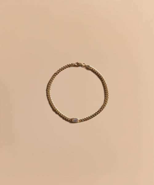 The Merit Emerald Cut Bracelet, featuring a small rectangular clasp, is elegantly arranged in a circle on a neutral beige background, highlighting the refined beauty of fine jewelry.