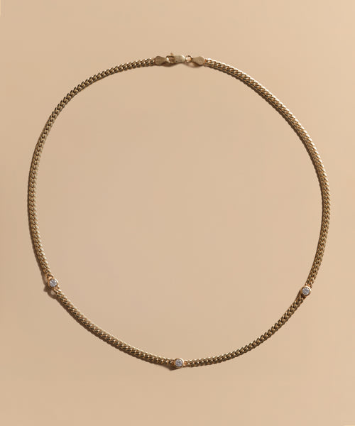 The Merit Round Cut Diamond Necklace features four evenly spaced round cut diamonds set in 14k gold, shown on a simple beige background—an elegant piece inspired by Jenni Kayne jewelry.