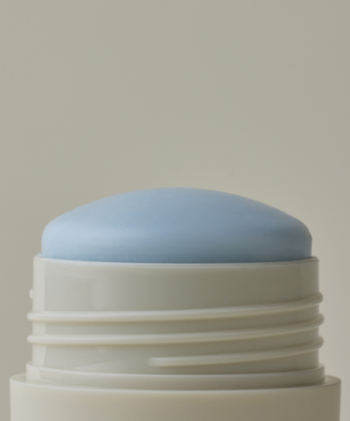 A close-up of the Microbiome Balancing Deodorant—a light blue, dome-shaped, aluminum-free stick in a white twist-up container made for sensitive skin—against a plain background.