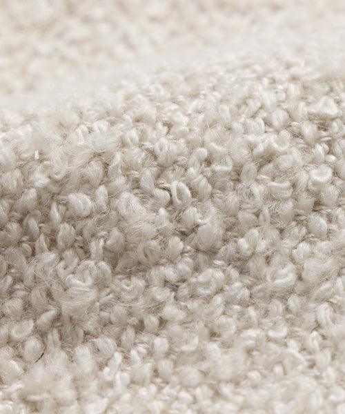 Close-up of a textured, cream-colored fabric with small loops and a soft, bumpy surface, like the Fabric Swatch Oyster Mini Boucle.