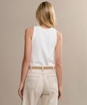 A person with long blonde hair is seen from behind, wearing a white sleeveless top and high-waisted light beige jeans, styled with the Mini Jules Belt, against a plain beige background.