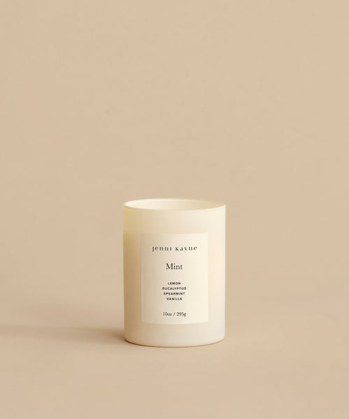 The Mint Glass Candle, hand-poured in Los Angeles, features lemon, eucalyptus, and vanilla scents in a frosted glass container with a minimalist jenni kayne label, displayed against a plain beige background.