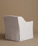 A white upholstered armchair with a matching back cushion, shown against a solid warm taupe background.
