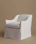 A white upholstered armchair with a matching back cushion, shown against a solid warm taupe background.