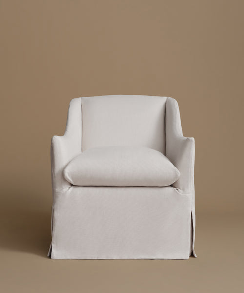 A white upholstered armchair with a matching back cushion, shown against a solid warm taupe background.