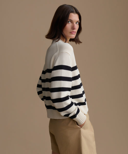 Woman wearing a black and white striped sweater against a beige background