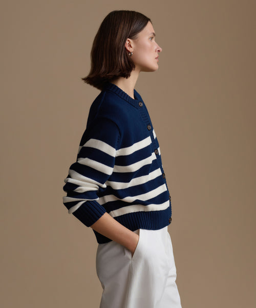 Woman wearing a navy and white striped sweater against a beige background