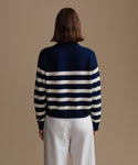 Woman wearing a navy and white striped sweater against a beige background