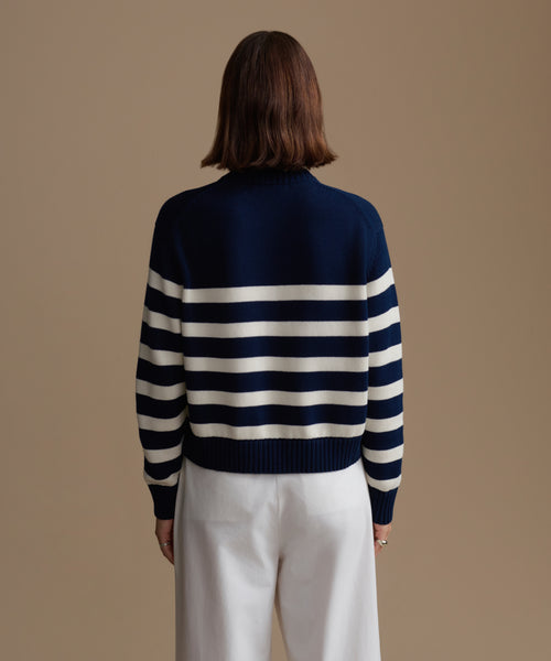 Woman wearing a navy and white striped sweater against a beige background