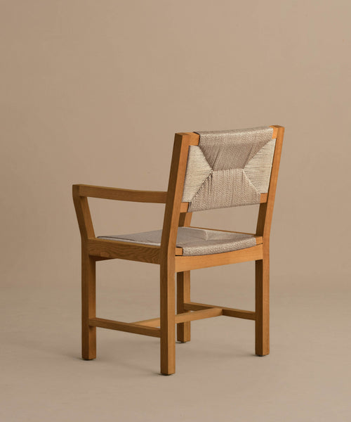 The Outdoor Montecito Dining Arm Chair Frame features armrests and a beige woven ECOLENE seat and backrest, set on a neutral floor with a plain beige background.