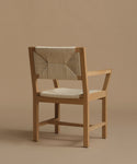 The back of a vintage inspired dining chair with wood against a beige background.