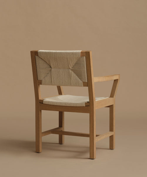 The back of a vintage inspired dining chair with wood against a beige background.