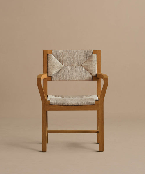 The Outdoor Montecito Dining Arm Chair Frame features a teak wood construction, cream ECOLENE woven seat and backrest, angular armrests, and a modern minimalist design. Corrosion-resistant, shown against a plain beige background.