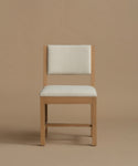 An ivory upholstered dining chair with oak wood set against a beige background.