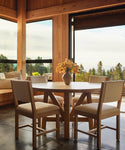 Upholstered dining chairs with a round oak wood dining table in a dining room setting.