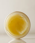 A top-down view of an open jar of Moisture Rich Balm reveals its yellowish, semi-solid texture with Sea Buckthorn Oil against a plain light background.