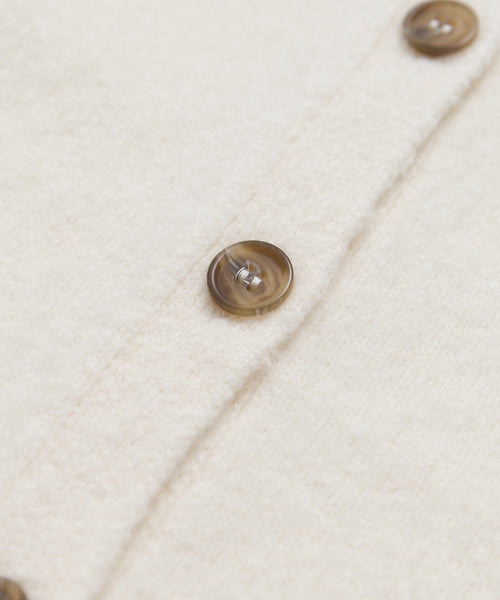 Close-up of the Murphy Cardigan’s soft cream fabric with brown marbled buttons along the seam, highlighting its luxurious knit and elegant ivory shade.