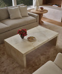 An ivory parchment coffee table in a living room setting with a natural upholstered sofa. 